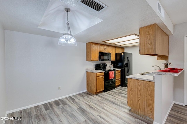 kitchen with light hardwood / wood-style floors, sink, black appliances, and hanging light fixtures