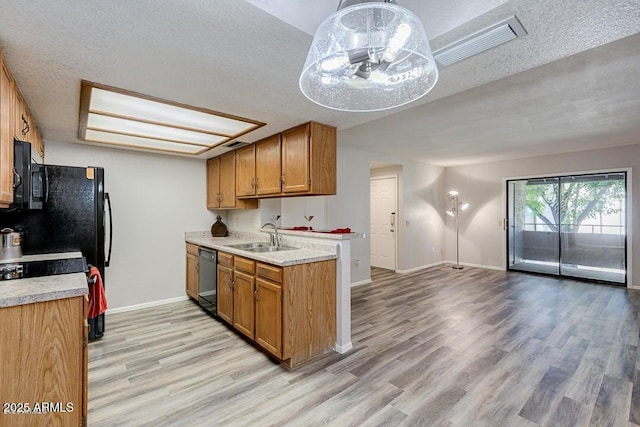 kitchen featuring decorative light fixtures, black dishwasher, sink, light wood-type flooring, and a textured ceiling