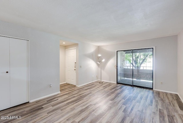 empty room featuring a textured ceiling and light hardwood / wood-style flooring