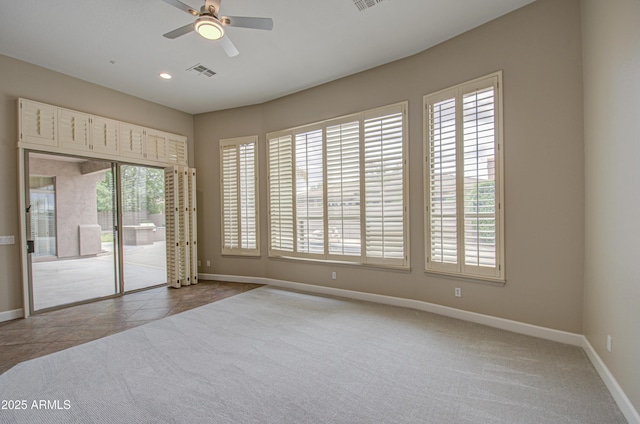 unfurnished room featuring ceiling fan, tile patterned flooring, visible vents, baseboards, and carpet