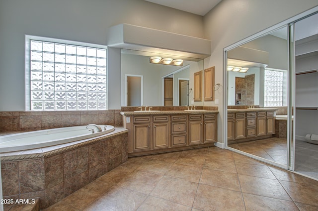 full bath with a bath, double vanity, a sink, and tile patterned floors