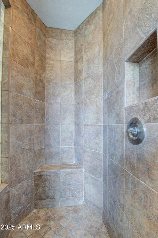 bathroom featuring a tile shower and a textured ceiling