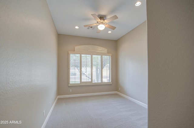 empty room with light carpet, ceiling fan, visible vents, and baseboards