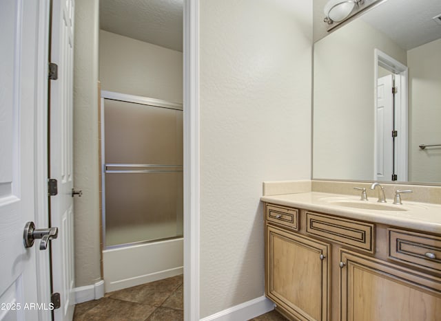 full bathroom with baseboards, shower / bath combination with glass door, vanity, and a textured ceiling