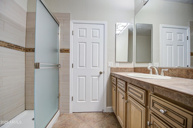 full bath with a stall shower, vanity, and tile patterned floors