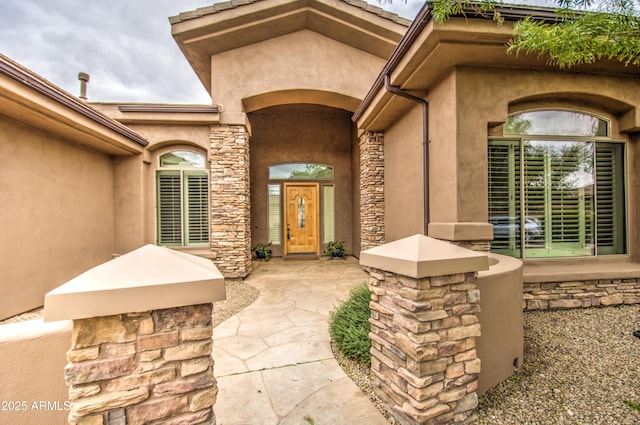 entrance to property featuring stone siding and stucco siding