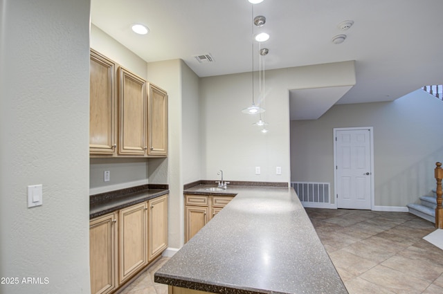 kitchen with dark countertops, a peninsula, visible vents, and a sink