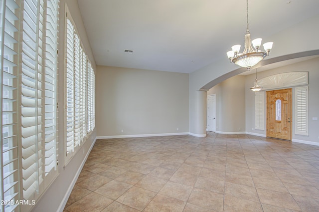 unfurnished room featuring arched walkways, light tile patterned floors, visible vents, an inviting chandelier, and baseboards