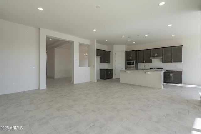 16367 W Desert Mirage Dr, Surprise, AZ 85388 - unfurnished living room featuring baseboards, a sink, and recessed lighting