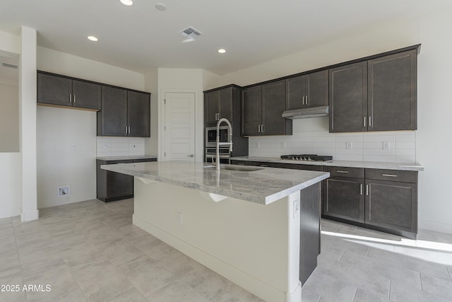 16367 W Desert Mirage Dr, Surprise, AZ 85388 - kitchen featuring recessed lighting, under cabinet range hood, a center island with sink, decorative backsplash, and appliances with stainless steel finishes