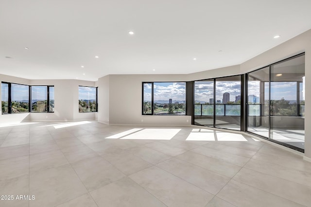 spare room featuring recessed lighting, a healthy amount of sunlight, and baseboards