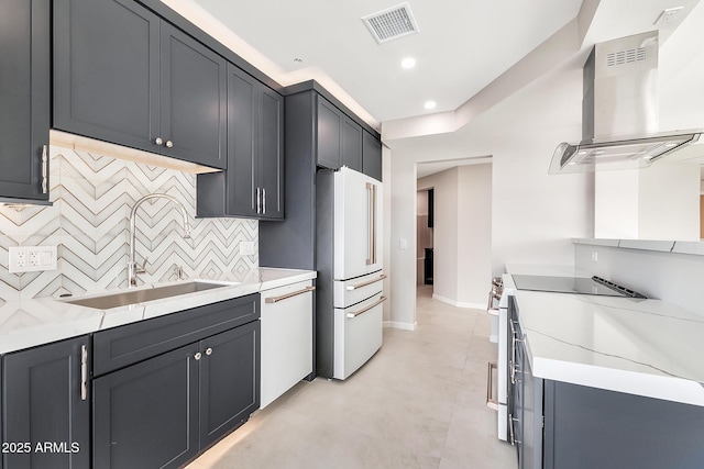 kitchen featuring white appliances, visible vents, wall chimney exhaust hood, a sink, and backsplash