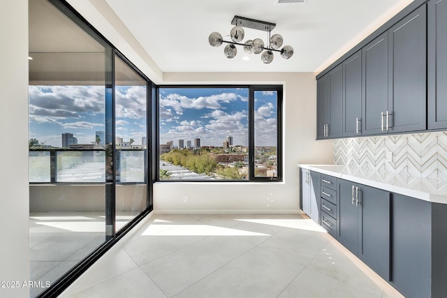 interior space with a view of city, gray cabinets, light countertops, backsplash, and light tile patterned flooring