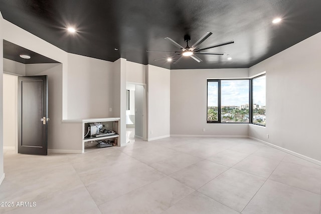 unfurnished living room with a ceiling fan, baseboards, and light tile patterned floors