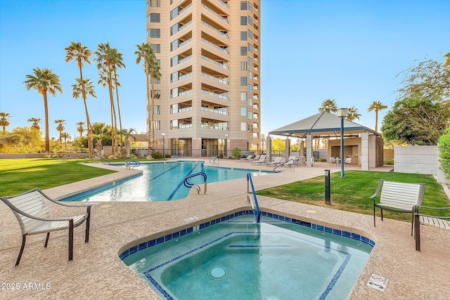 community pool with a lawn, a hot tub, a gazebo, a patio area, and fence