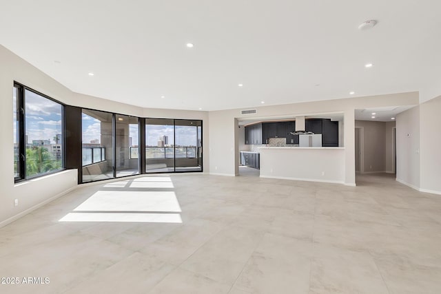 unfurnished living room with visible vents, plenty of natural light, and baseboards