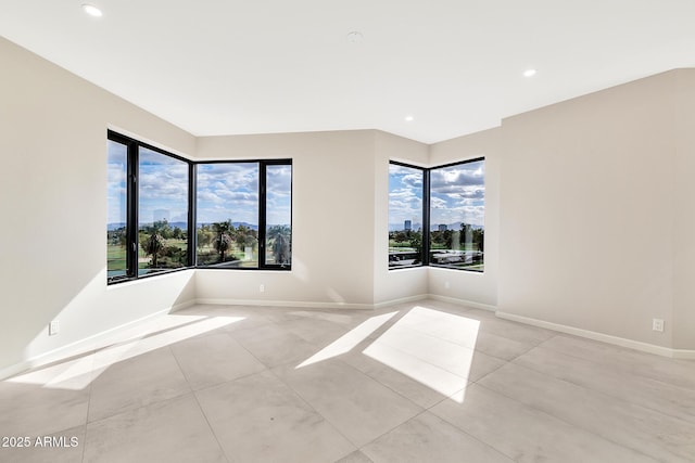 spare room with light tile patterned floors, recessed lighting, a wealth of natural light, and baseboards