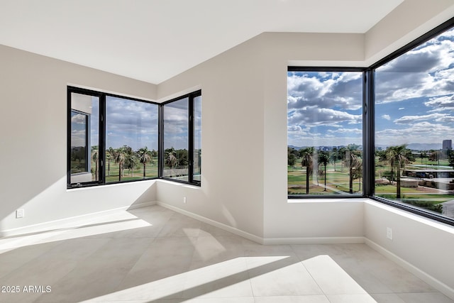 tiled empty room with a wealth of natural light and baseboards