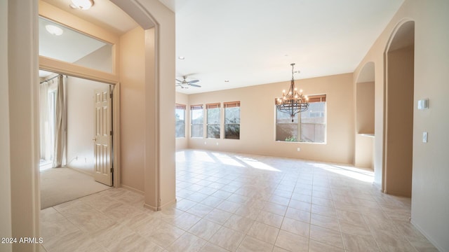 tiled spare room with ceiling fan with notable chandelier