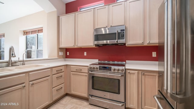 kitchen with light brown cabinets, sink, light tile patterned floors, and stainless steel appliances