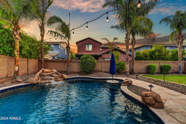 pool at dusk with a fenced in pool and a fenced backyard