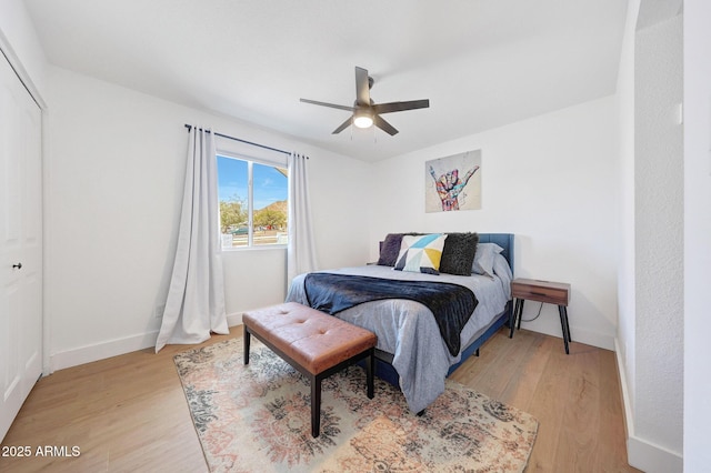 bedroom featuring baseboards, ceiling fan, a closet, and light wood finished floors