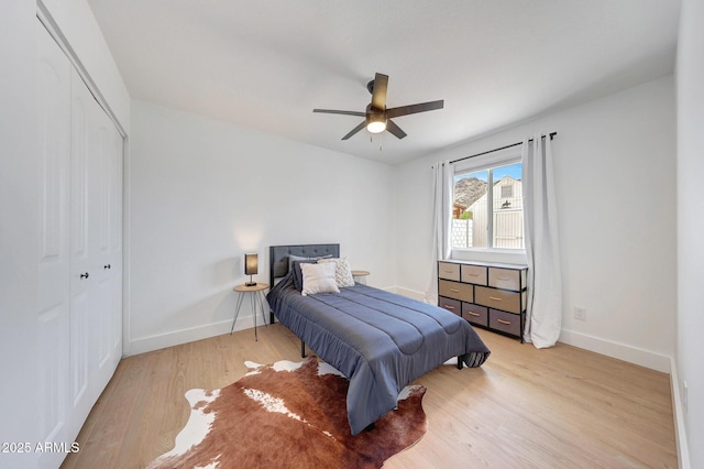 bedroom with a closet, light wood finished floors, a ceiling fan, and baseboards