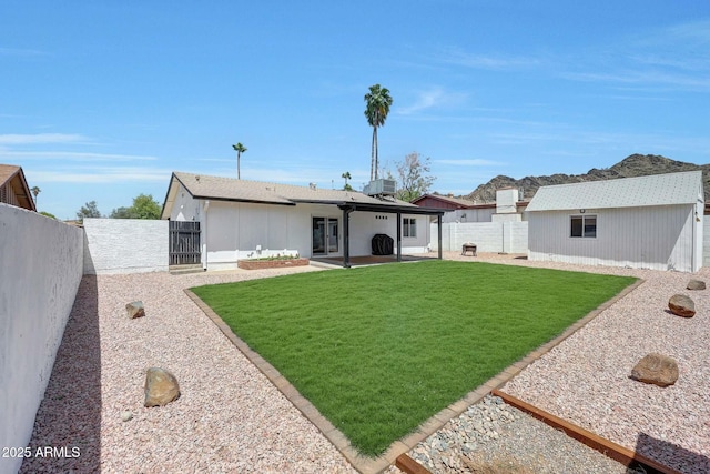 rear view of property with a lawn, a gate, a fenced backyard, and a patio area