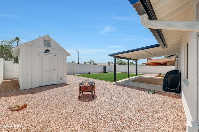 view of patio / terrace featuring an outdoor structure, a storage shed, a fenced backyard, and an outdoor fire pit