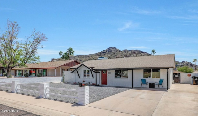single story home featuring a mountain view, a fenced front yard, and roof with shingles