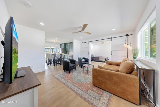 living area with light wood finished floors, a ceiling fan, recessed lighting, and a barn door