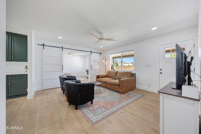 living room with light wood-style flooring, a barn door, ceiling fan, baseboards, and recessed lighting