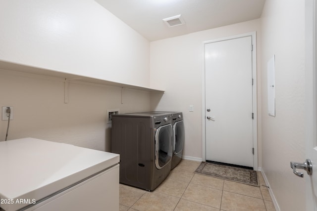 clothes washing area featuring visible vents, baseboards, washing machine and dryer, laundry area, and light tile patterned flooring