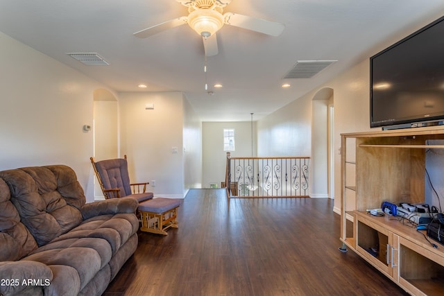 living room with arched walkways, visible vents, and wood finished floors