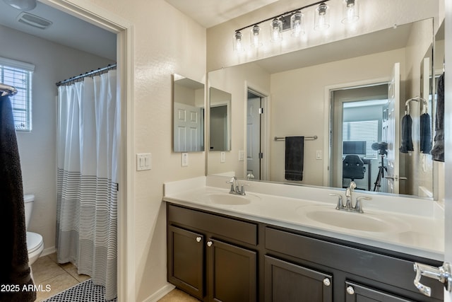 full bath with double vanity, tile patterned floors, toilet, and a sink