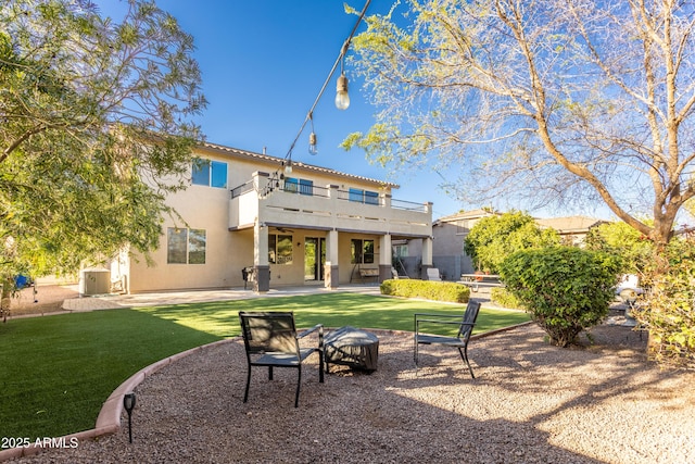 back of house featuring a yard, a patio area, a balcony, and stucco siding