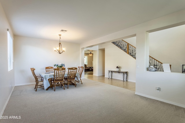 carpeted dining space with stairs, ceiling fan with notable chandelier, baseboards, and visible vents