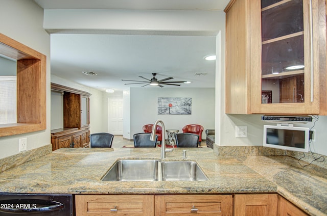 kitchen featuring ceiling fan, sink, light stone counters, and black dishwasher