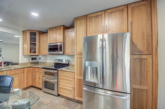 kitchen with stainless steel appliances, light stone counters, and sink