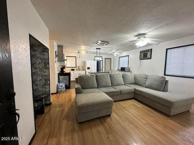 404 E Forest Dr, Payson, AZ 85541 - living area featuring a textured ceiling, ceiling fan, light wood-type flooring, and a wall mounted air conditioner