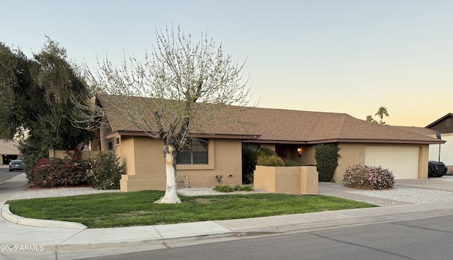 ranch-style house featuring driveway, a garage, a front lawn, and stucco siding