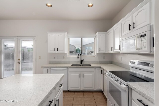 kitchen with white cabinets, a sink, white appliances, recessed lighting, and light tile patterned floors