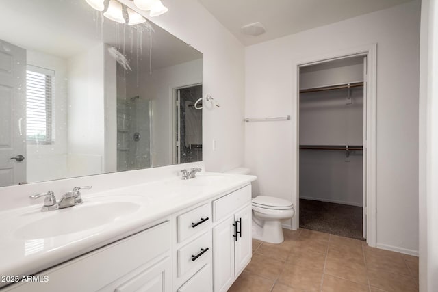 bathroom with a walk in closet, a sink, toilet, tile patterned floors, and a stall shower
