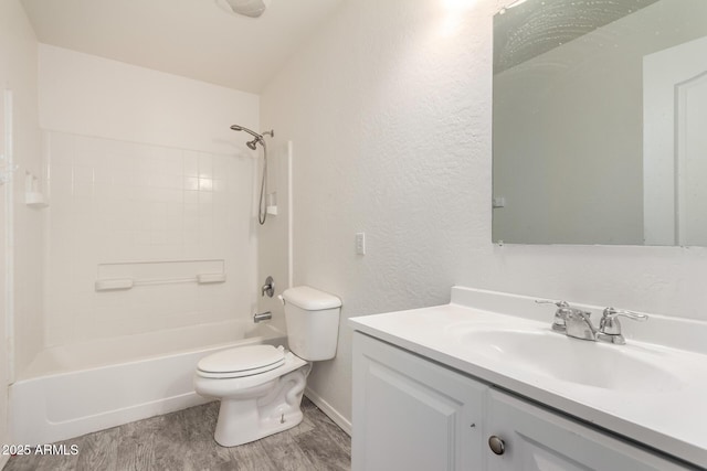 bathroom with a textured wall, vanity, toilet, wood finished floors, and  shower combination