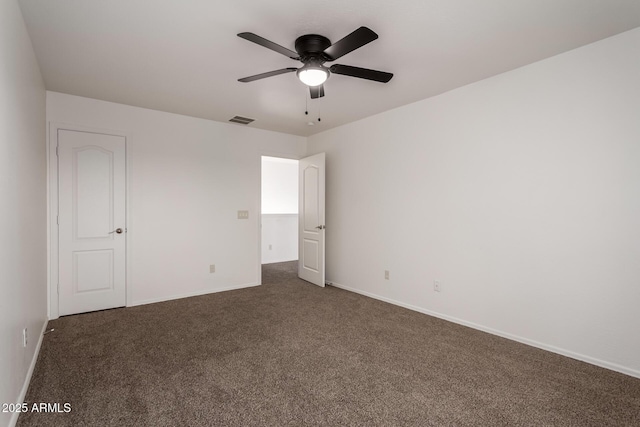 spare room with baseboards, ceiling fan, visible vents, and dark carpet