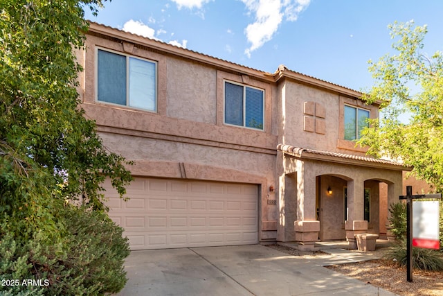 view of front of house featuring a tiled roof, a garage, stucco siding, and driveway