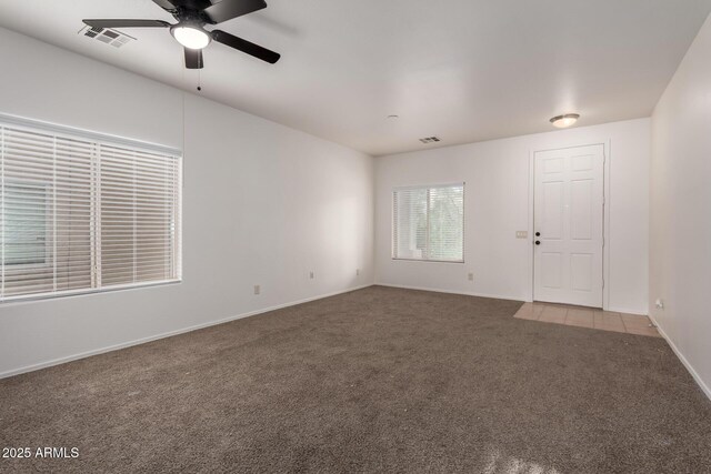 carpeted spare room featuring ceiling fan, visible vents, and baseboards