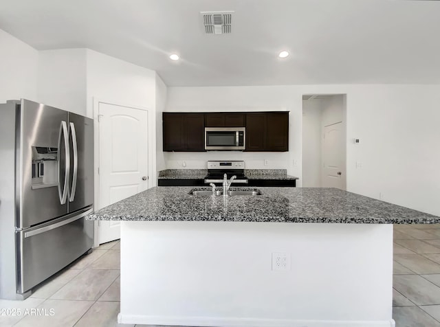 35337 W San Alvarez Ave, Maricopa, AZ 85138 - kitchen featuring appliances with stainless steel finishes, a sink, light tile patterned flooring, dark stone counters, and dark brown cabinets