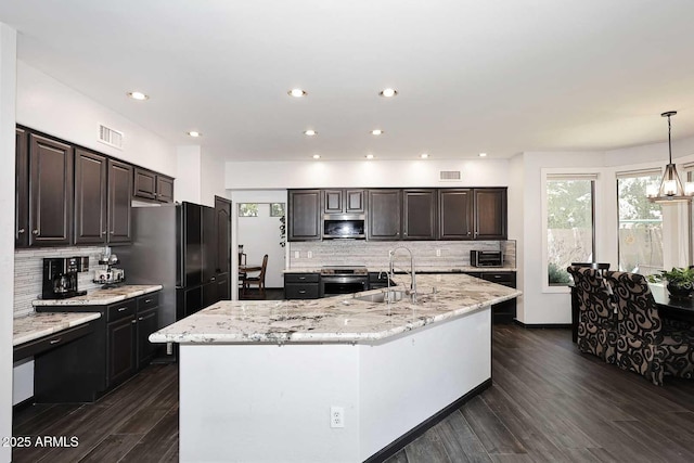 kitchen featuring appliances with stainless steel finishes, a sink, backsplash, dark wood-style floors, and a large island