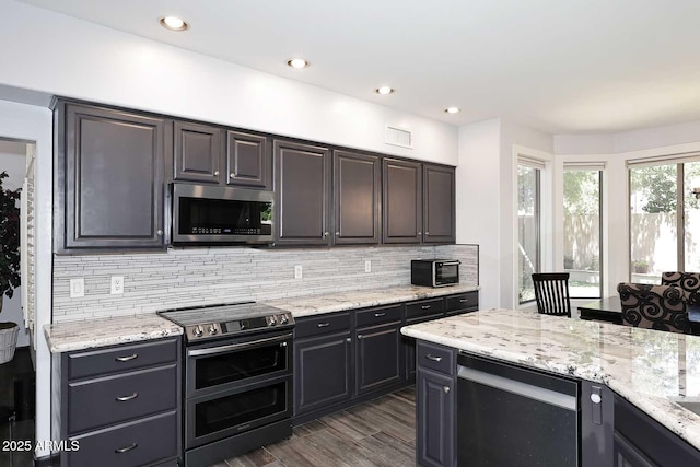 kitchen with appliances with stainless steel finishes, decorative backsplash, light stone countertops, dark wood-type flooring, and recessed lighting